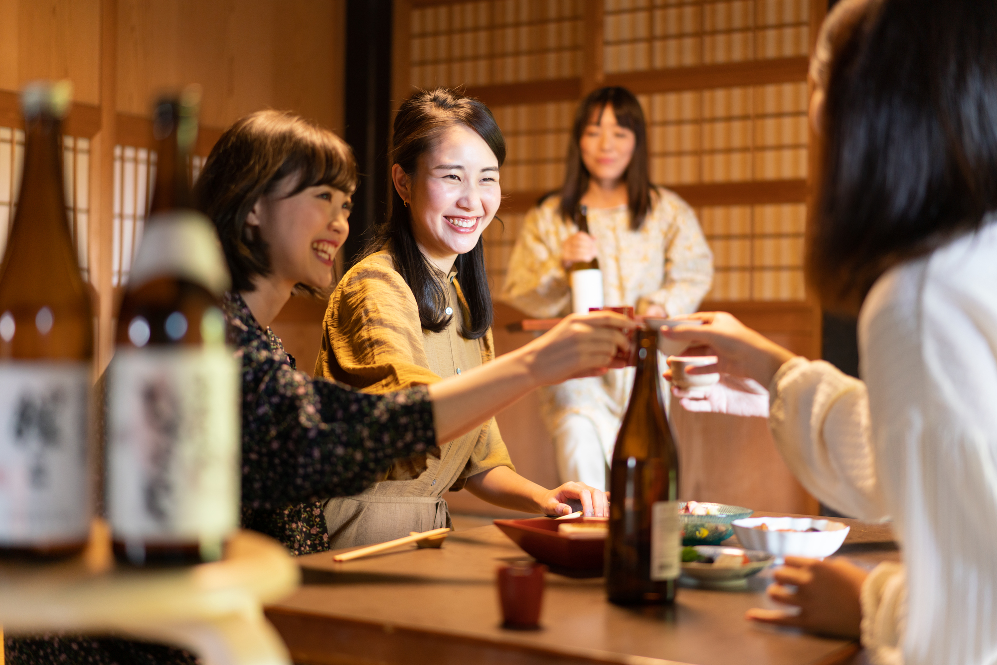古民家風の和室でお酒を酌み交わし、笑顔で乾杯する女性たち