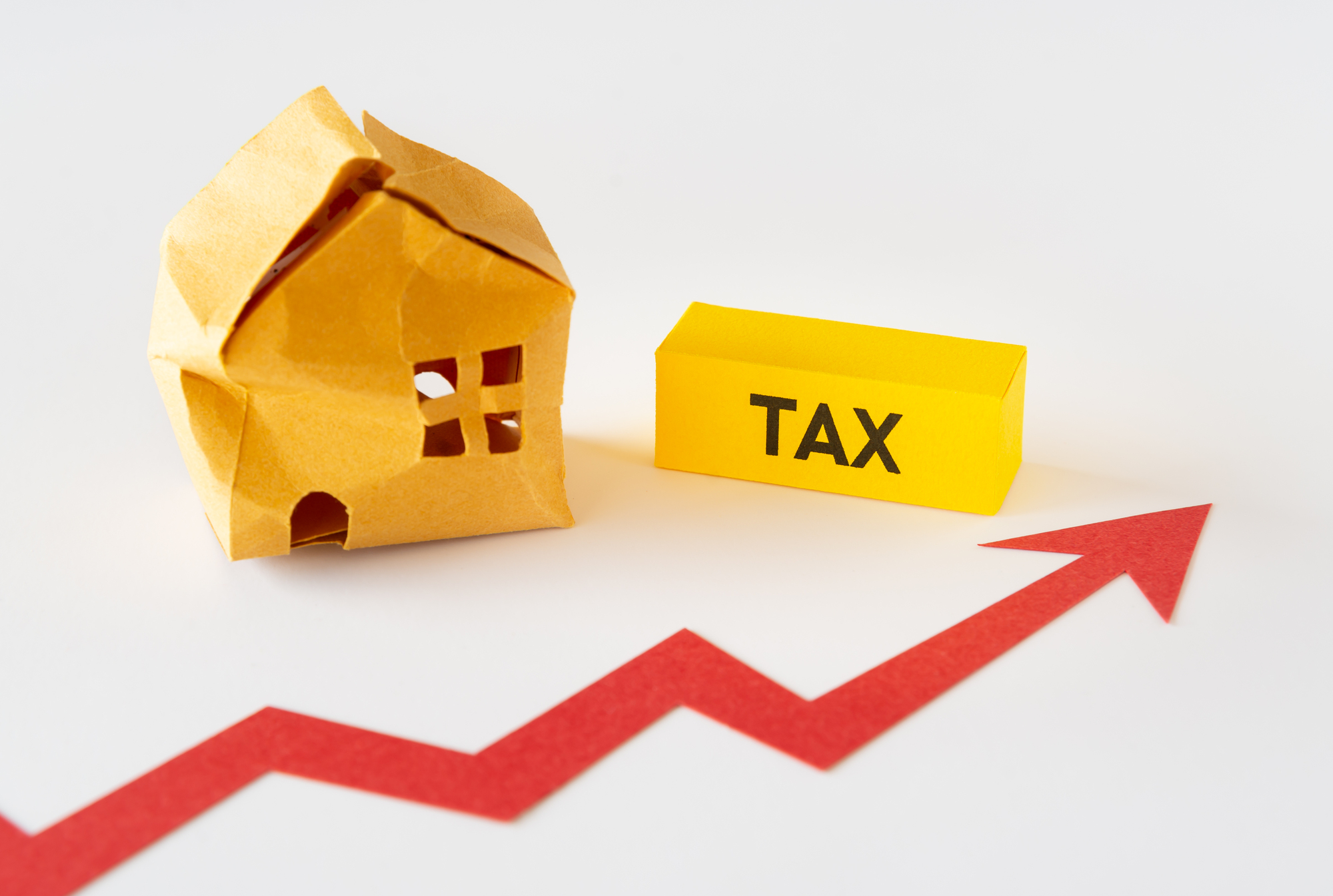 傷んだ家の模型と「TAX」の文字、右肩上がりの赤い矢印