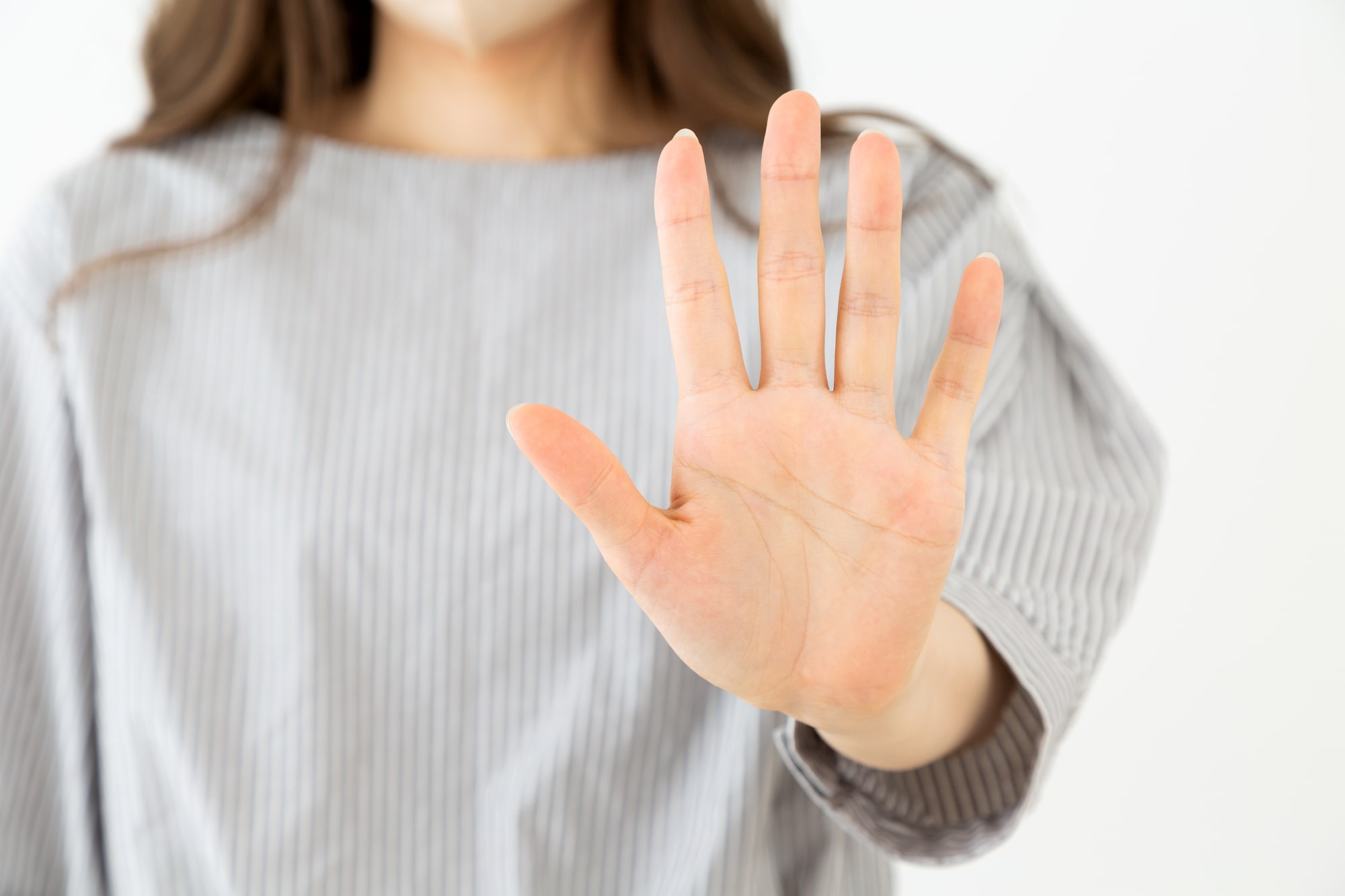 手のひらを前に向け、制止する仕草をする女性
