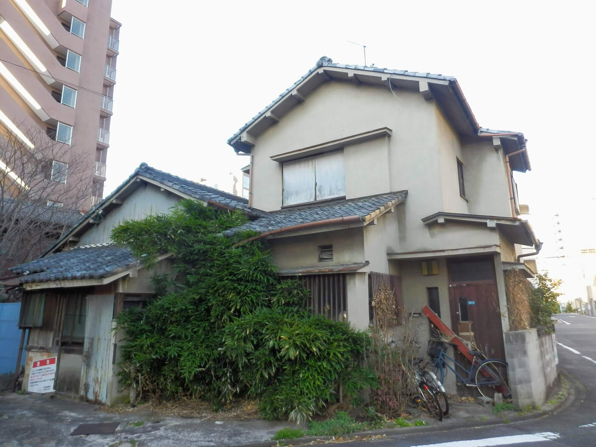 庭木や草が生い茂る2階建ての住宅