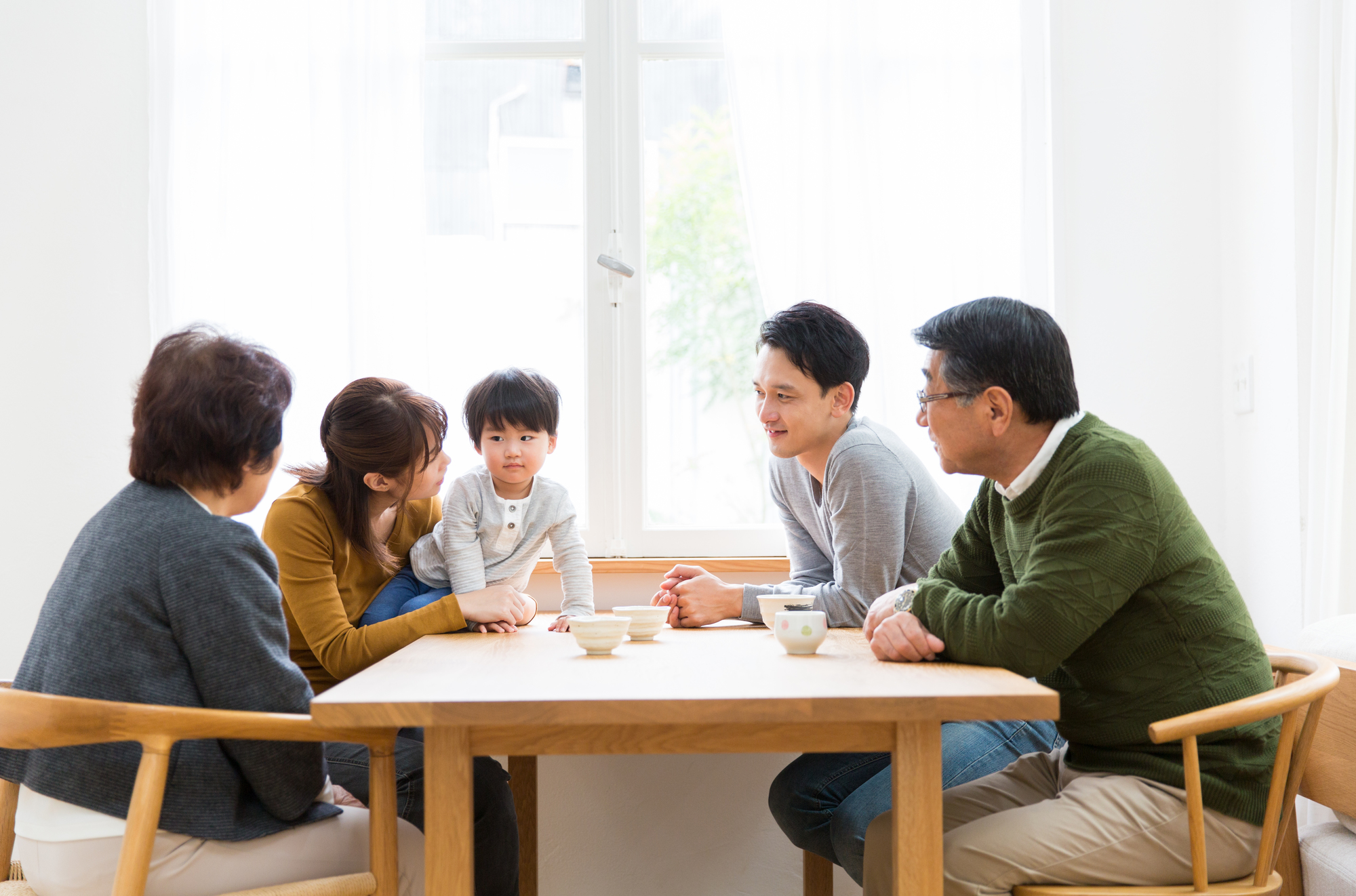テーブルを囲み、笑顔で会話する三世代の家族