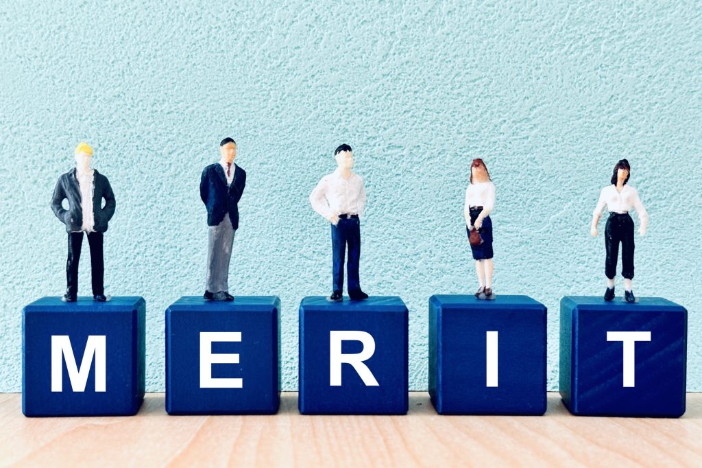 MERITと書かれたブロックと人のミニチュア