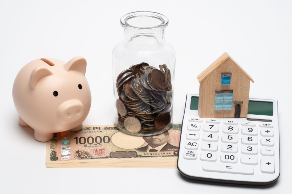 個人向け国債の運用や資産形成をイメージさせる、豚の貯金箱・小銭が入った瓶・一万円札・電卓・家型オブジェクト