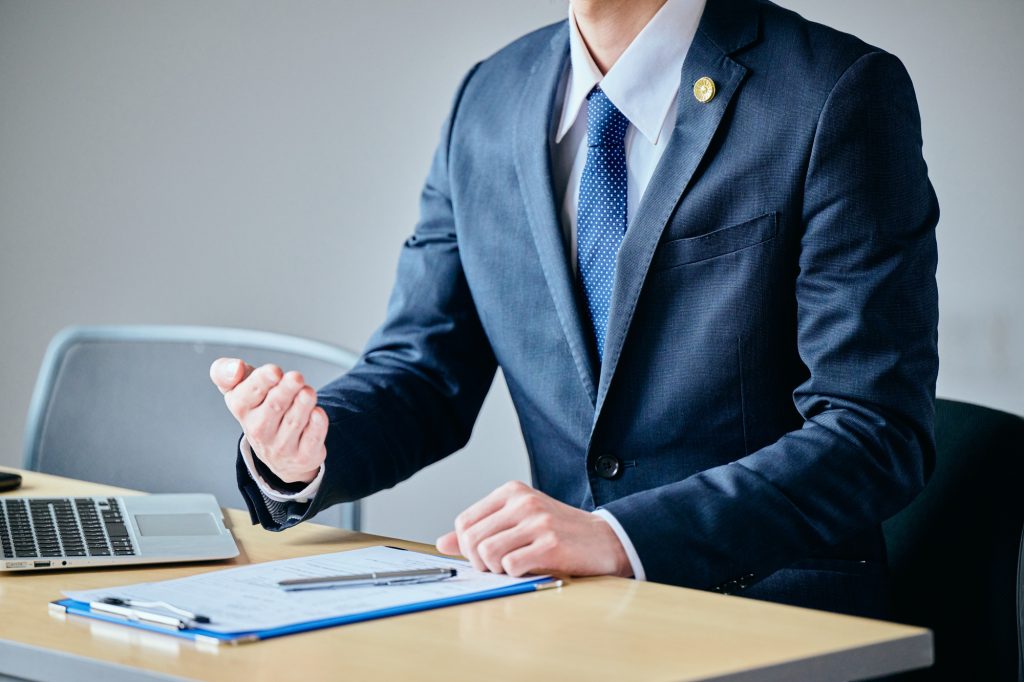 売主物件と仲介物件の違いや契約時の説明をイメージさせる、デスクで説明を行うスーツ姿の男性